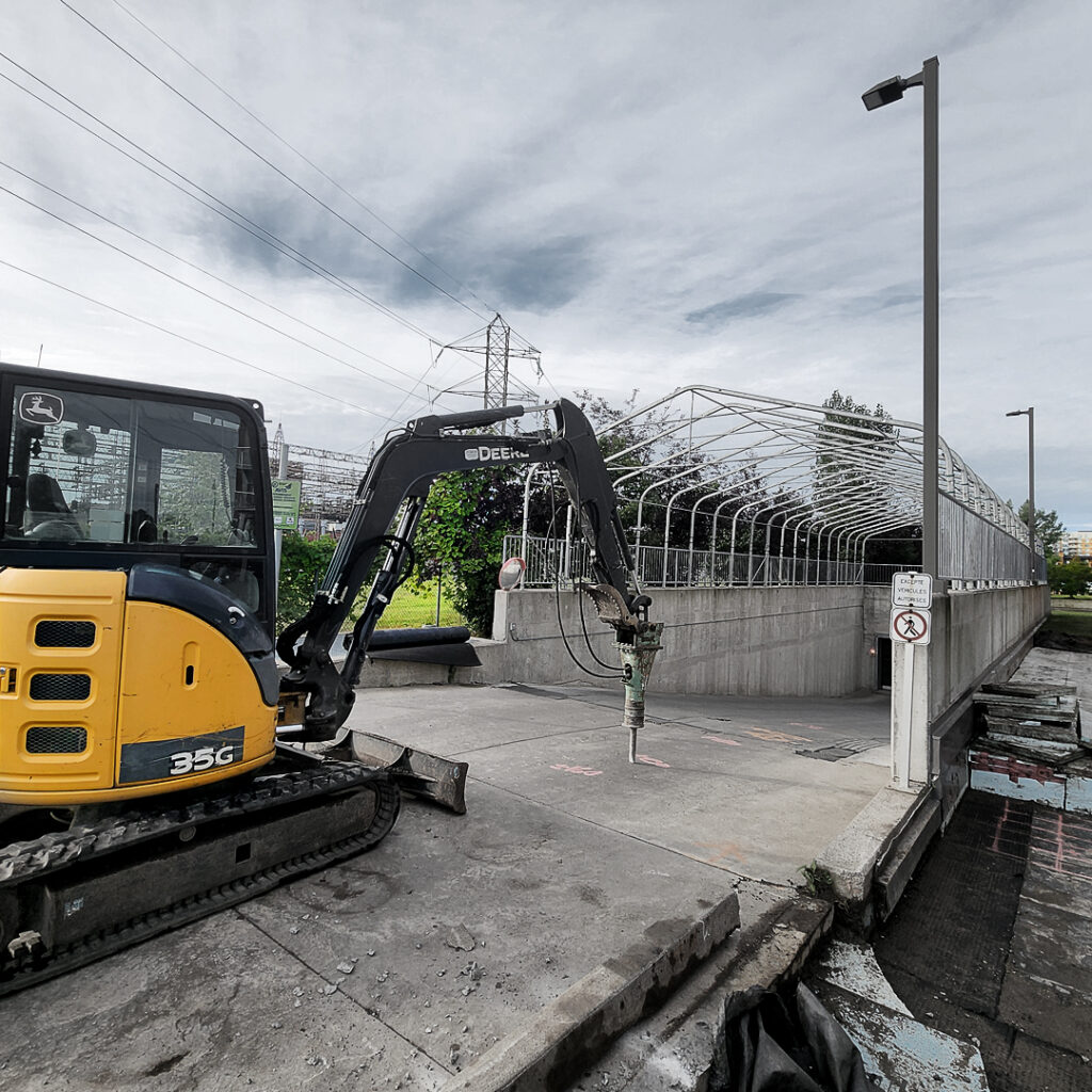 Une excavatrice munie d'un marteau piqueur hydraulique s'apprète au cassage d'une dalle de béton.